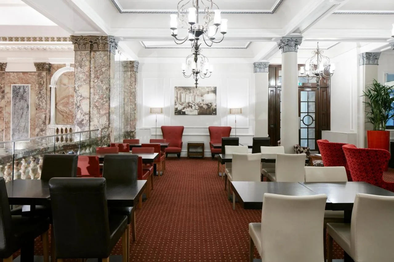 a dining room with tables and chairs and a chandelier at Club Quarters Hotel Trafalgar Square, London in London