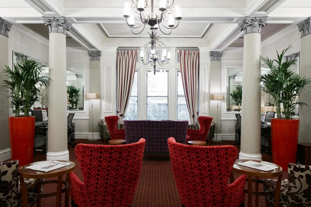 a dining room with red chairs and a chandelier at Club Quarters Hotel Trafalgar Square, London in London