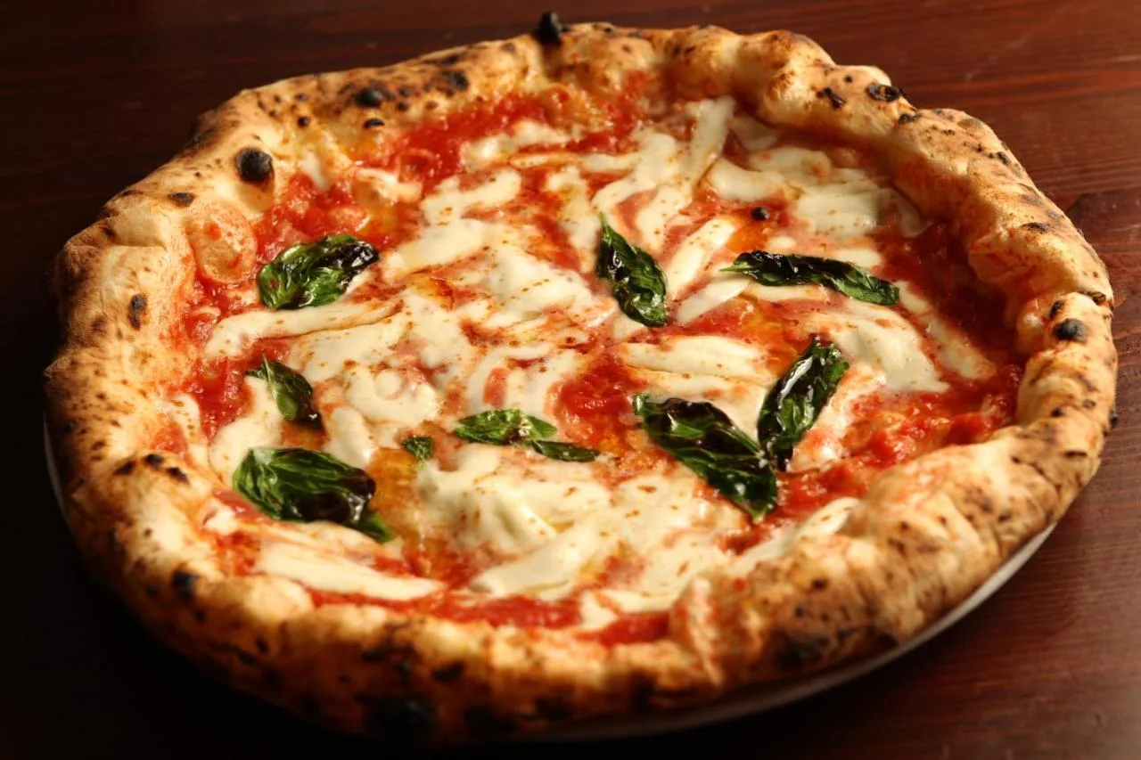 a pizza with cheese and spinach on a table at Club Quarters Hotel Trafalgar Square, London in London