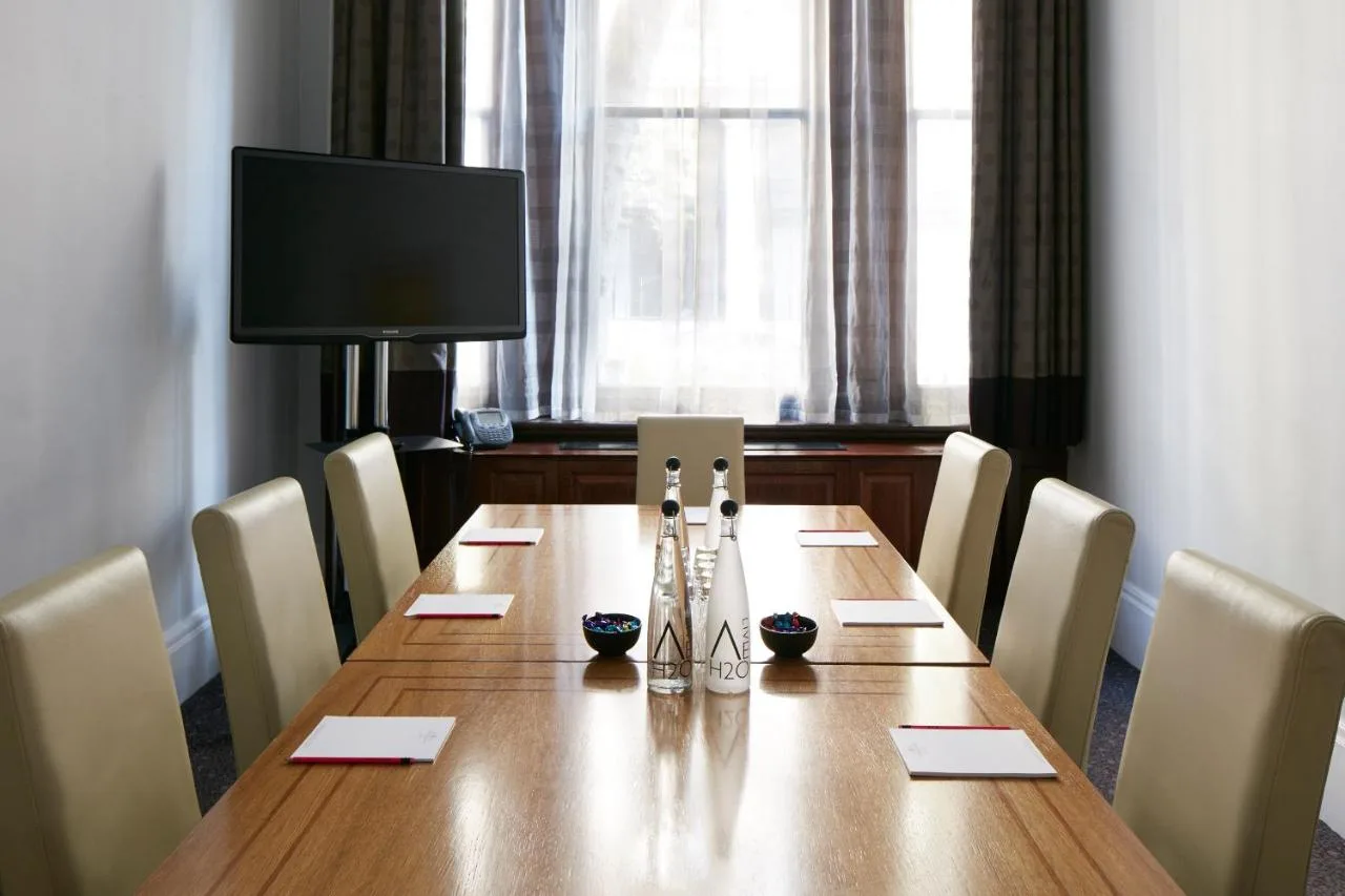 a conference room with a long wooden table with chairs at Club Quarters Hotel Trafalgar Square, London in London